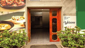 The exterior of Santhi Inn with a welcoming sign, a wooden door, and potted plants. - FabHotel Santhi Inn (Puducherry)
