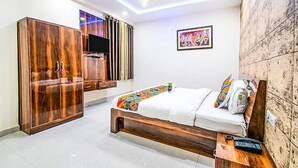 A bedroom with a bed, a wardrobe, a TV, and a wall with a picture. - Fabhotel Elysian Grand (Lucknow)
