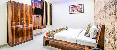 Un dormitorio con cama, armario, televisión y un cuadro en la pared.