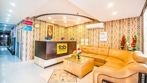 A hotel lobby with a reception desk, a sofa, and patterned wallpaper. - Fabhotel Elysian Grand (Lucknow)