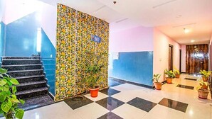 A hotel lobby with a checkered floor, a staircase, a floral wall, and potted plants. - Fabhotel Elysian Grand (Lucknow)