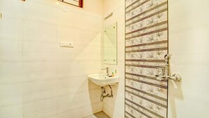 Un baño pequeño con lavamanos, espejo y puerta de ducha con diseño a rayas.