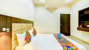 Una habitación de hotel con una cama, cabecera de madera, televisor en la pared y una puerta.