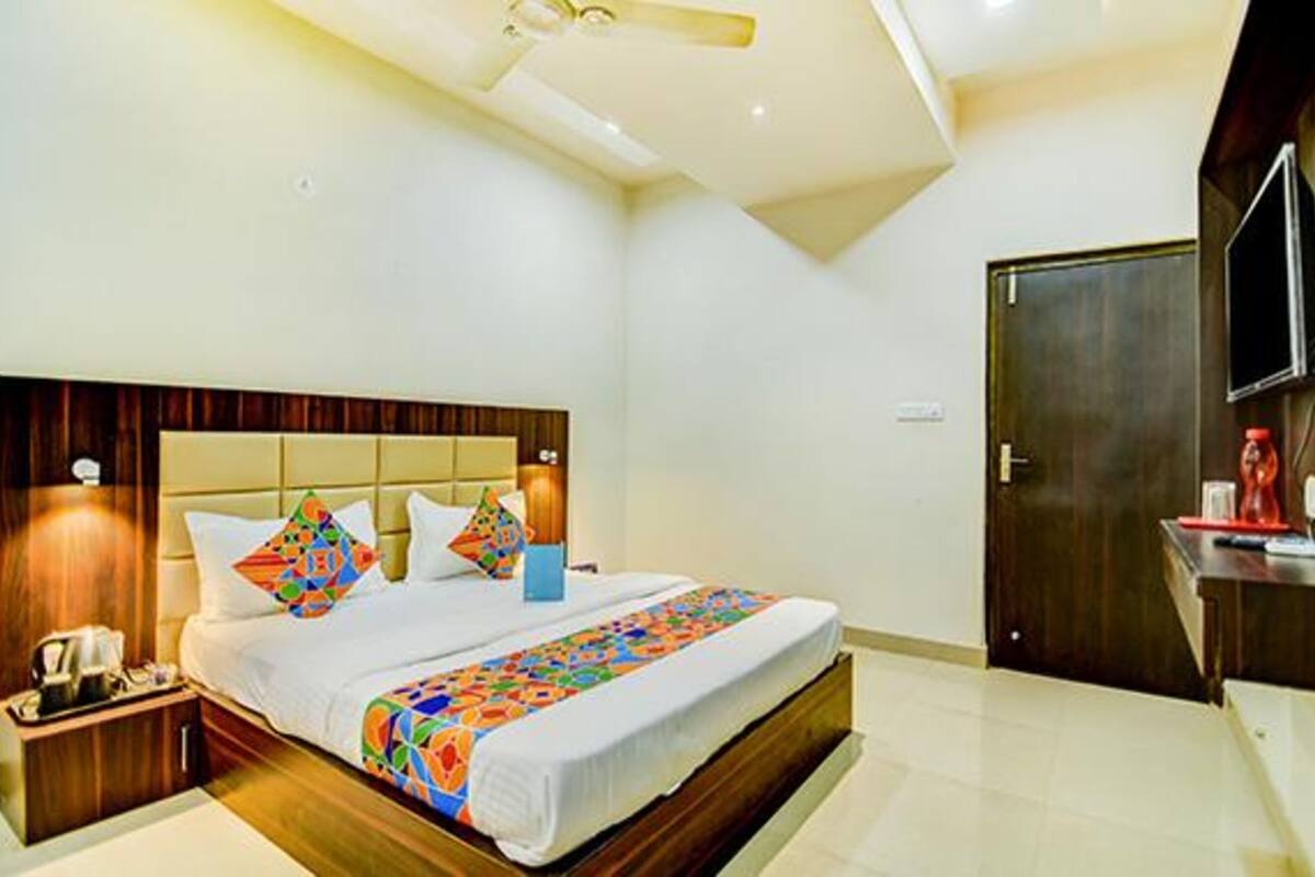 A hotel room with a large bed, bedside tables, a TV, and a wooden door.