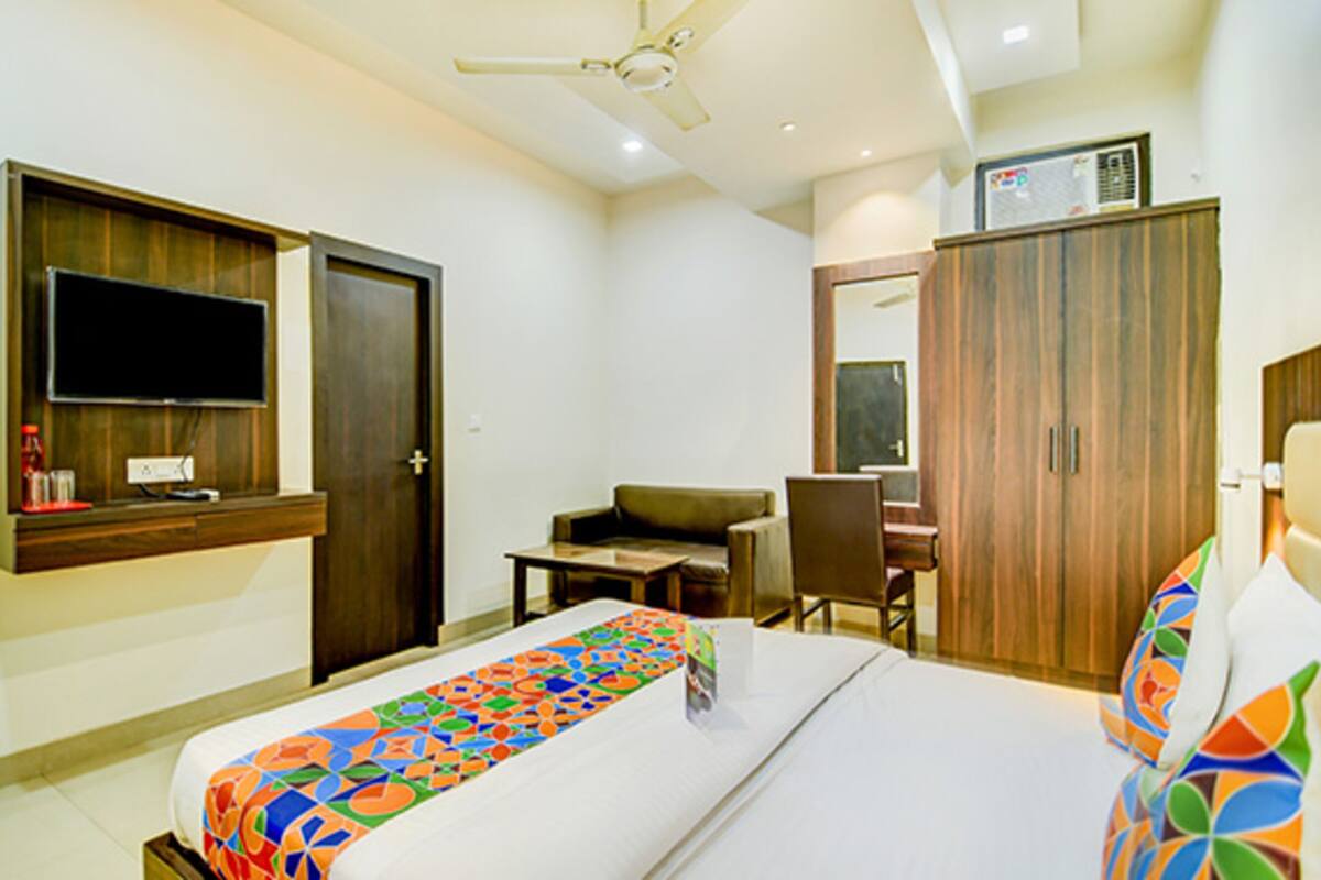 A hotel room with a bed, a desk, a chair, a television, and a wardrobe.