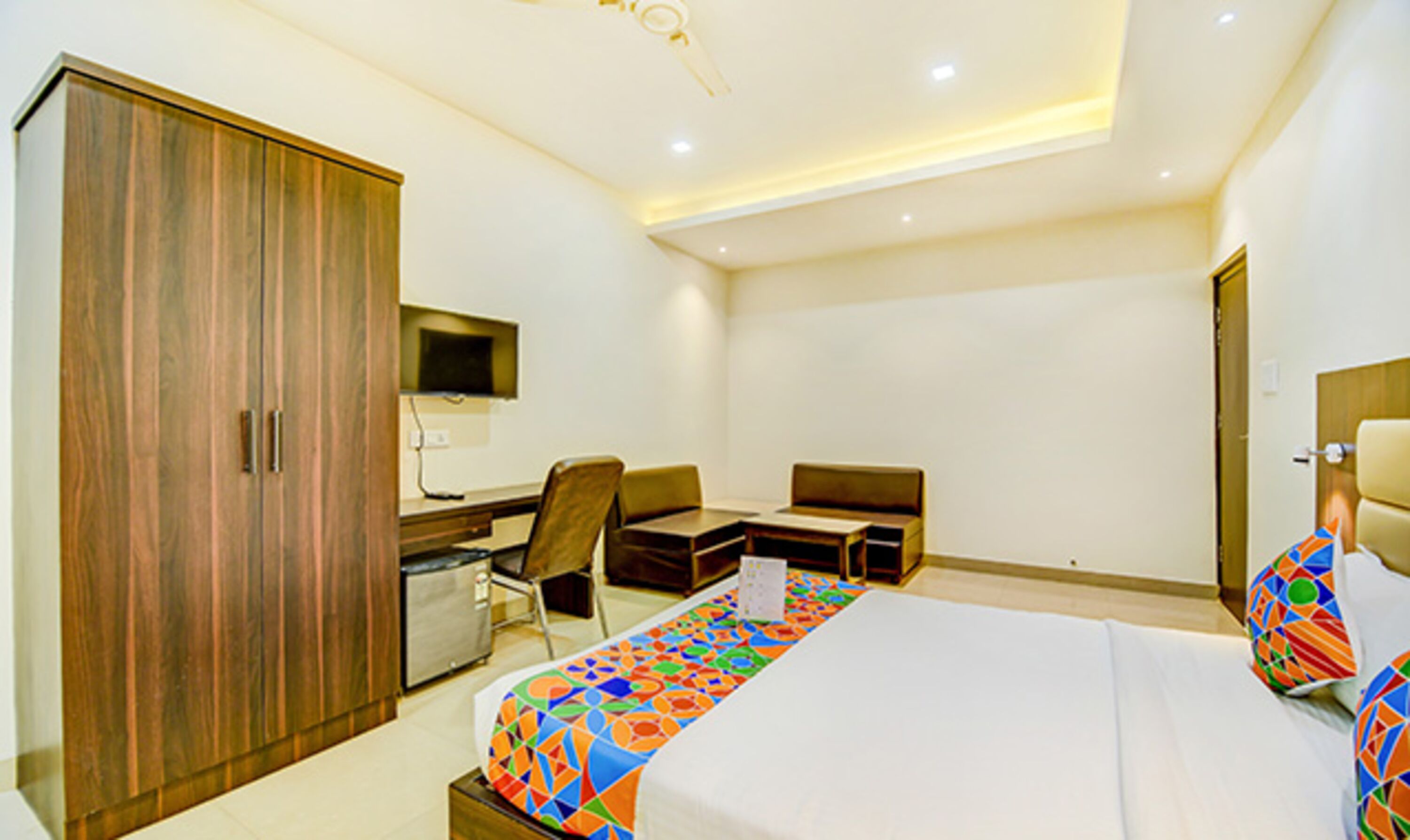 Une chambre d’hôtel moderne équipée d’un grand lit, d’un bureau, d’une chaise, d’une armoire et d’un téléviseur.