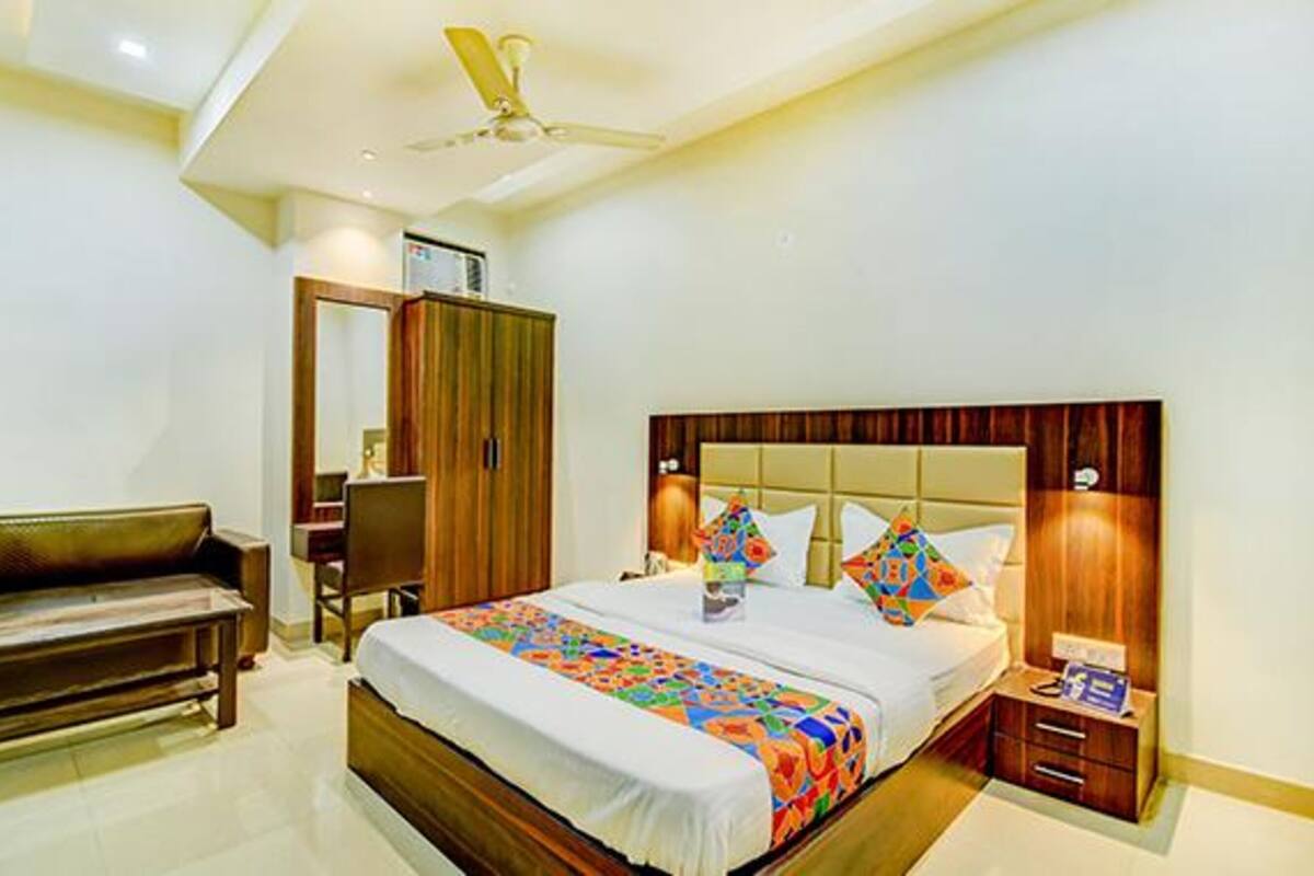 A bedroom with a bed, a desk, a wardrobe, and a ceiling fan.