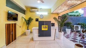 A hotel reception area with a reception desk, a clock, and potted plants. - Fabhotel Kiara (Gurugram)