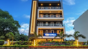 A multi-story building with a 'fabHOTELS' sign, balconies, and a well-lit entrance. - Fabhotel Kiara (Gurugram)