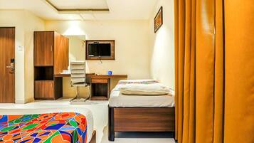 A hotel room with two beds, a desk, a chair, a television, and a wardrobe.