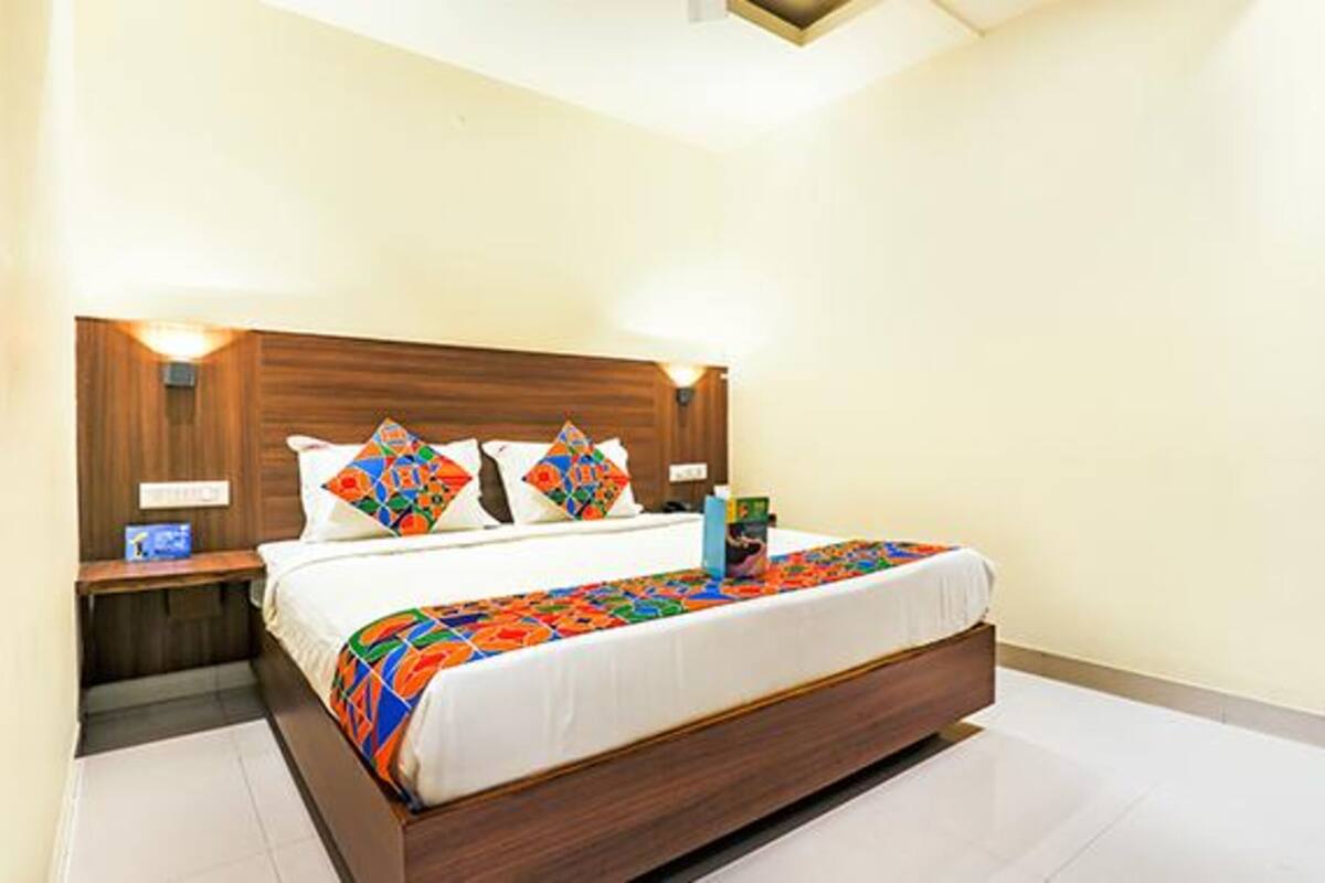 A neatly made bed with a colorful bedspread, a wooden headboard, and two bedside tables with lamps.