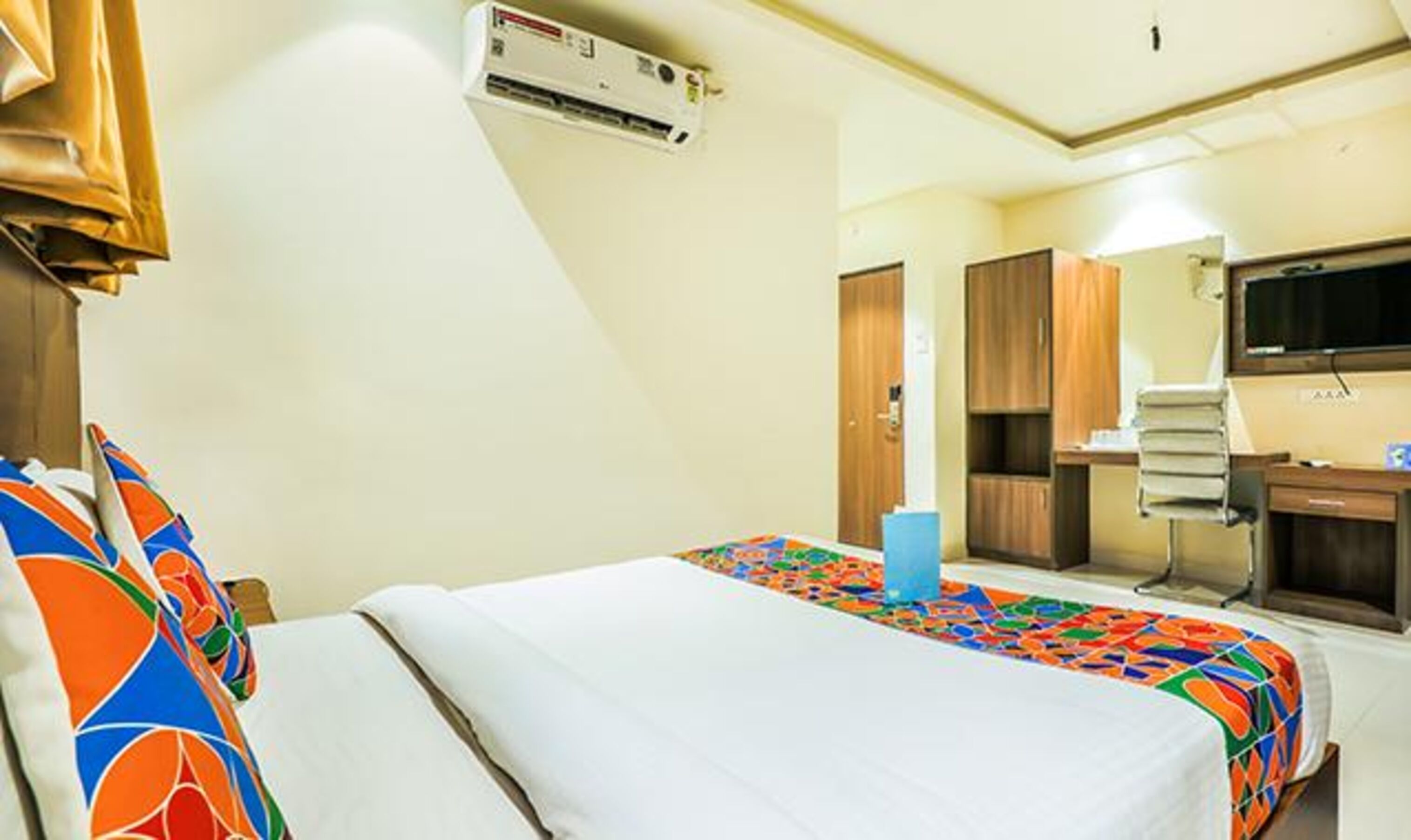 Une chambre d’hôtel équipée d’un lit, d’un bureau, d’une chaise, d’une télévision et d’un appareil de climatisation.