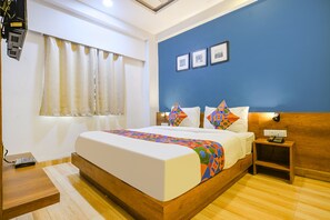 A bedroom with a bed, wooden nightstand, and a wall-mounted telephone. - FabHotel Hello Homz (Indore)
