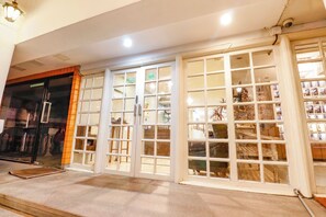 Une façade d’immeuble avec de grandes portes vitrées, une entrée bien visible et une caméra de surveillance.