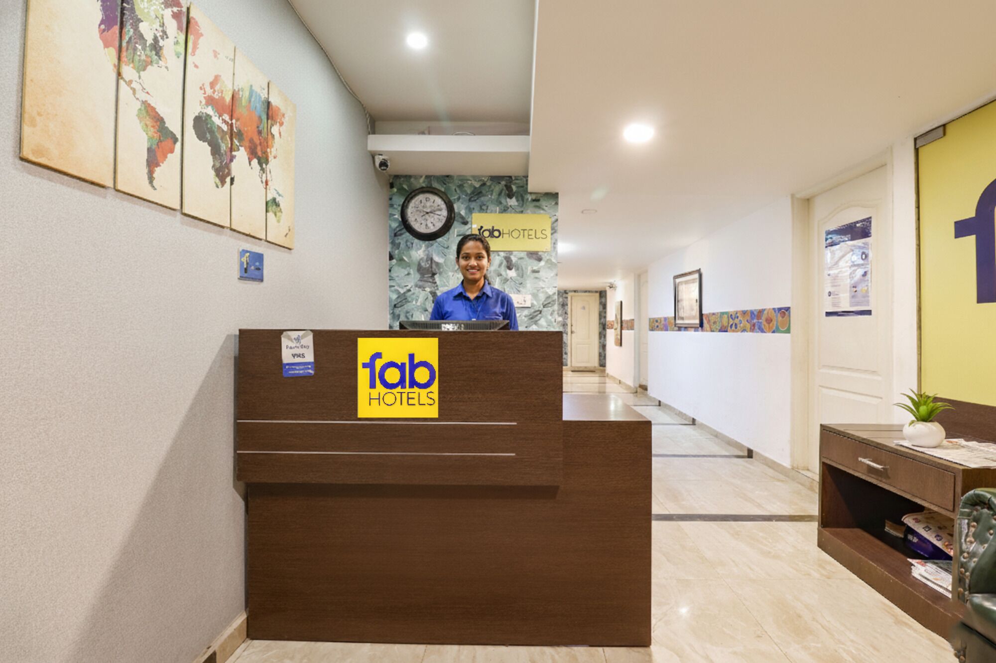 A hotel reception desk with a clock and a world map on the wall.