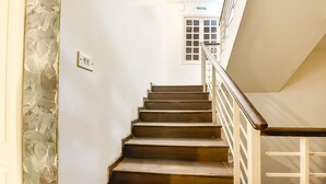 Una escalera con peldaños de madera y barandillas blancas que sube a un piso superior.
