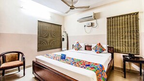 A hotel room with a bed, a chair, a desk, and a ceiling fan. - Fabhotel Aditya Yatri Nivas (Tirupati)