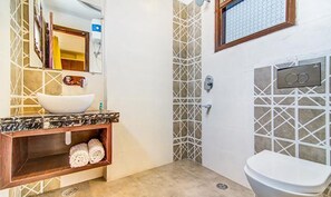 A bathroom with a white sink, marble countertop, wooden vanity, and a white toilet.
