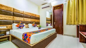 A bedroom with a large bed, a wooden headboard, a bedside table, and a wardrobe. - FabHotel Nayyar Inn (Amritsar)
