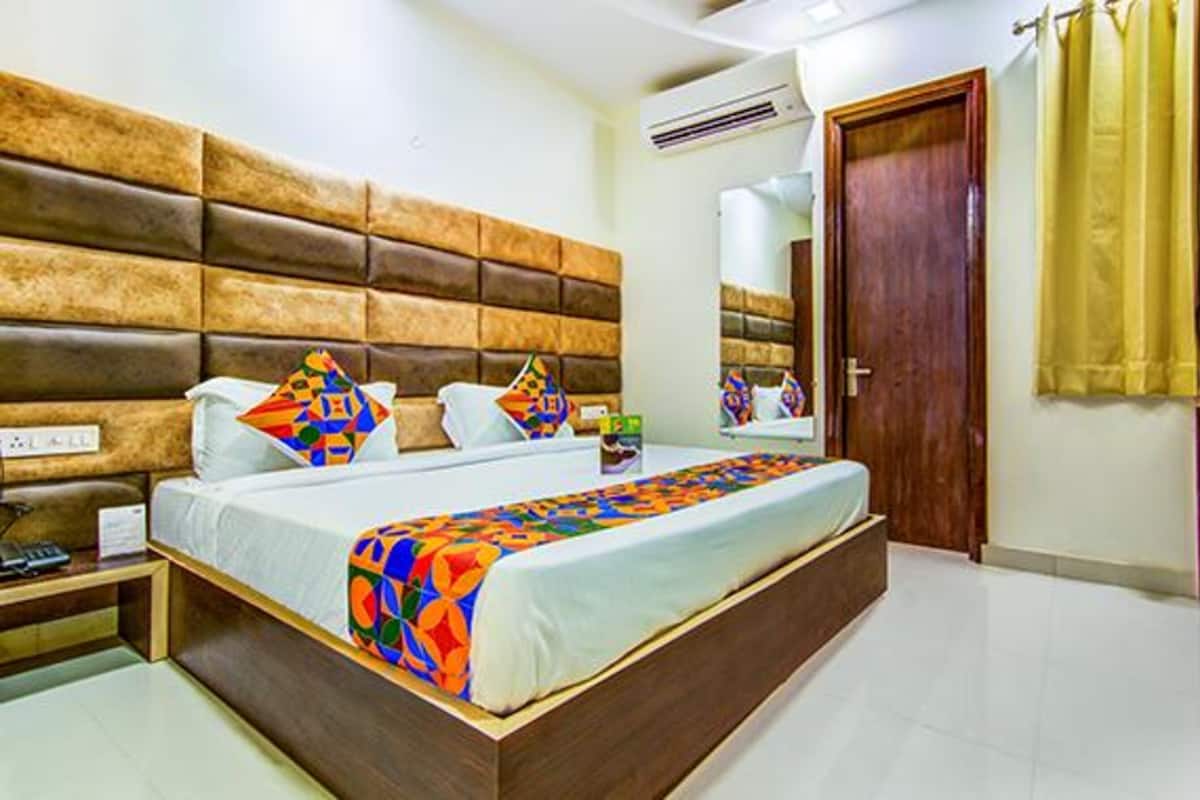 A bedroom with a large bed, a wooden headboard, a bedside table, and a wardrobe.