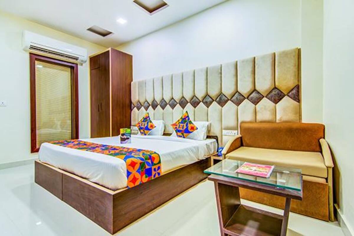 A hotel room with a bed, a sofa, a glass coffee table, and a wardrobe.
