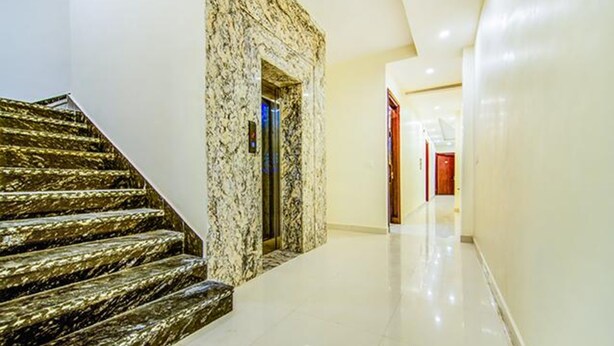 A marble staircase leading to an elevator, a hallway with a polished floor, and a door at the end. - FabHotel Nayyar Inn (Amritsar)