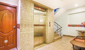Un ascensor con un cartel que dice 'Solo para personas' y una escalera que conduce a él.