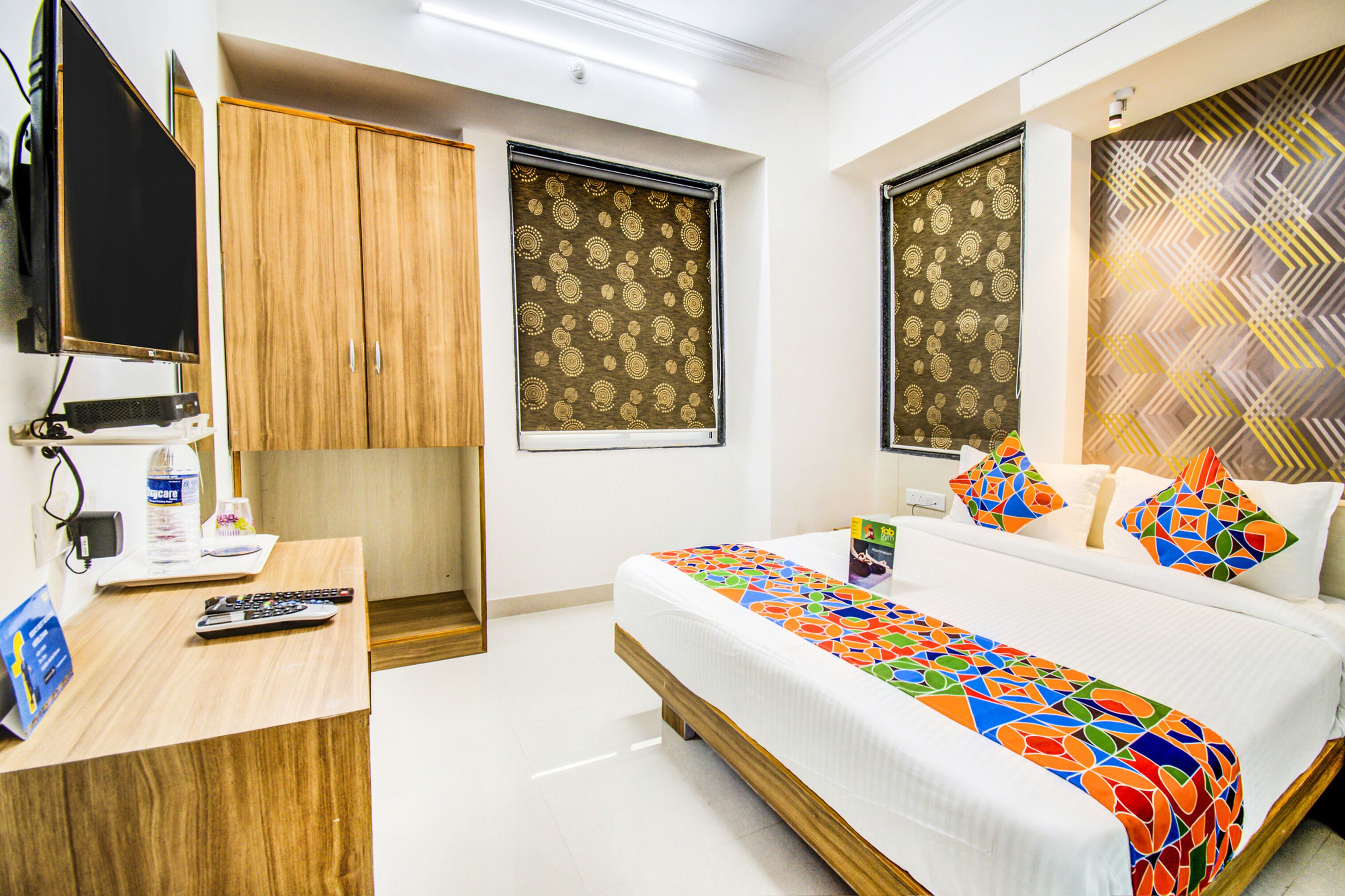 A hotel room with a bed, a desk, a television, and a wardrobe.