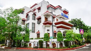 A multi-story building with balconies, a sign indicating a price range, and a street view. - Fabexpress Ullash Residency (Barasat)