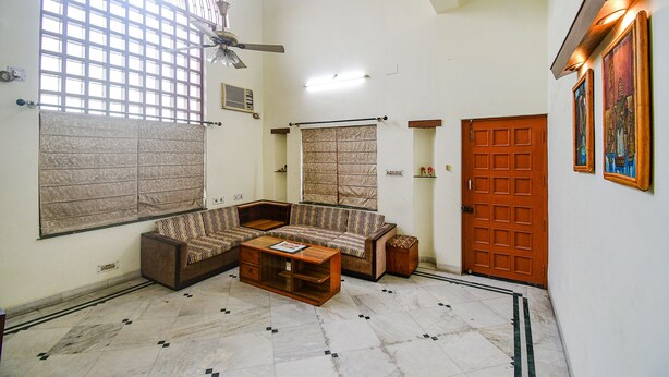 A spacious living area with a large window, a ceiling fan, and a wooden door. - Fabexpress Ullash Residency (Barasat)