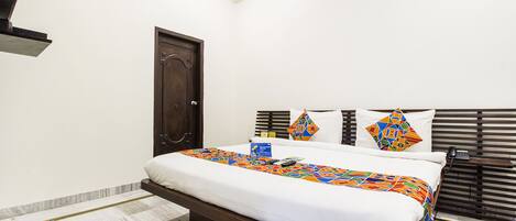 Habitación de hotel con cama, puerta, teléfono y ventana con persianas.