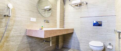 Ein modernes Badezimmer mit Marmorwand, Waschbecken mit Handtuchhalter, Toilette und Duschbrause.