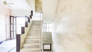 Una escalera de mármol en un interior moderno con techo alto y vistas al exterior.