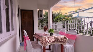 A balcony with a table and chairs, a door, and a view of the sky and greenery. - FabHotel Astoria House (Bidhannagar)
