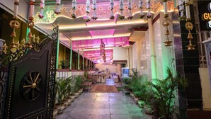 A corridor with a decorative gate, potted plants, and a reception area with a counter and chairs. - FabHotel Astoria House (Bidhannagar)