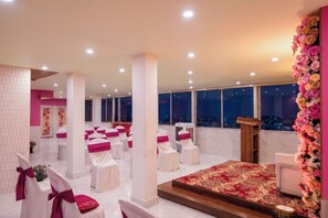Une chambre d’hôtel avec une grande fenêtre, un podium en bois et une composition florale.