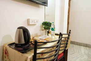 Una mesa de comedor con una tetera, una botella de agua y una planta.