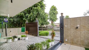 A gated entrance with a potted plant arrangement and a "PULL" sign. - FabHotel A&V Hospitality (Noida)