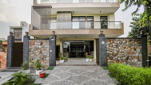 A two-story house with a stone facade, a balcony, and a paved entrance. - FabHotel A&V Hospitality (Noida)