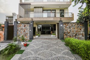 A two-story house with a stone facade, a balcony, and a paved entrance. - FabHotel A&V Hospitality (Noida)