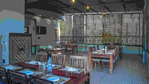 Un restaurante con varias mesas y sillas, un suelo estampado y lámparas colgantes.