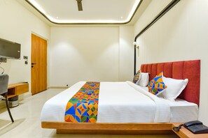 A hotel room with a large bed, a red headboard, a bedside table with a phone, and a TV mounted on the wall. - Vaibhavya Hotel and Restaurant-Udaipur (Udaipur)