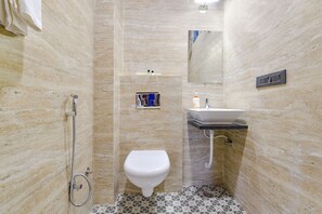 A bathroom with a shower, toilet, sink, and a mirror. - Vaibhavya Hotel and Restaurant-Udaipur (Udaipur)