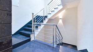 Una escalera moderna con barandillas metálicas y escalones oscuros, que sube a un piso superior.