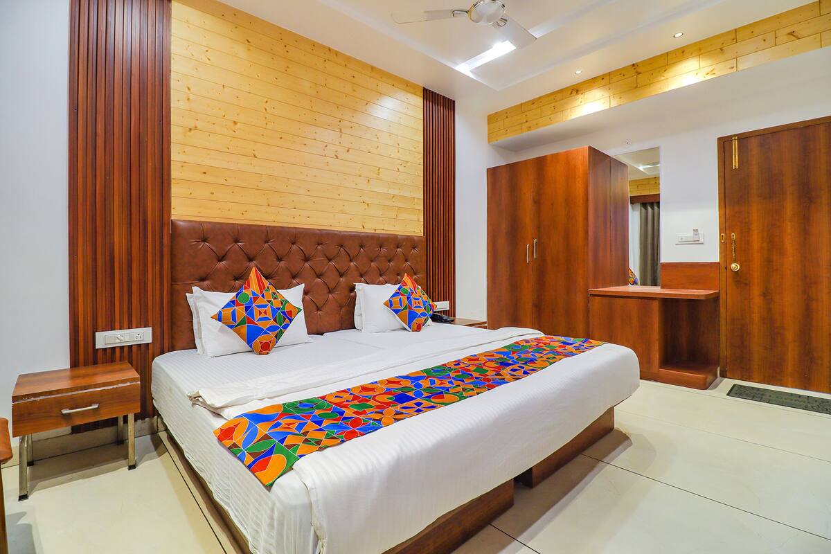 A bedroom with a large bed, wooden headboard, and a wooden wall panel.