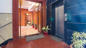 Un hall de hotel con un mostrador de recepción de madera, una zona de recepción y un ascensor azul.