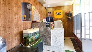 A hotel reception area with a wooden wall, a marble counter, and a fish tank. - Fabescape Panchkula Motels (Dera Bassi)