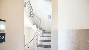 A staircase with metal railings and a wall-mounted emergency phone. - Fabescape Panchkula Motels (Dera Bassi)