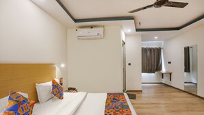 A hotel room with a bed, a ceiling fan, an air conditioning unit, and a bathroom visible through an open door. - Fabhotel F9 Sector 58 (Noida)