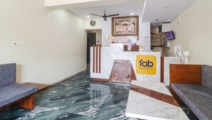 A hotel reception area with marble flooring, a reception desk, a clock, a ceiling fan, and a television. - Fabhotel Lotus Park (Visakhapatnam)